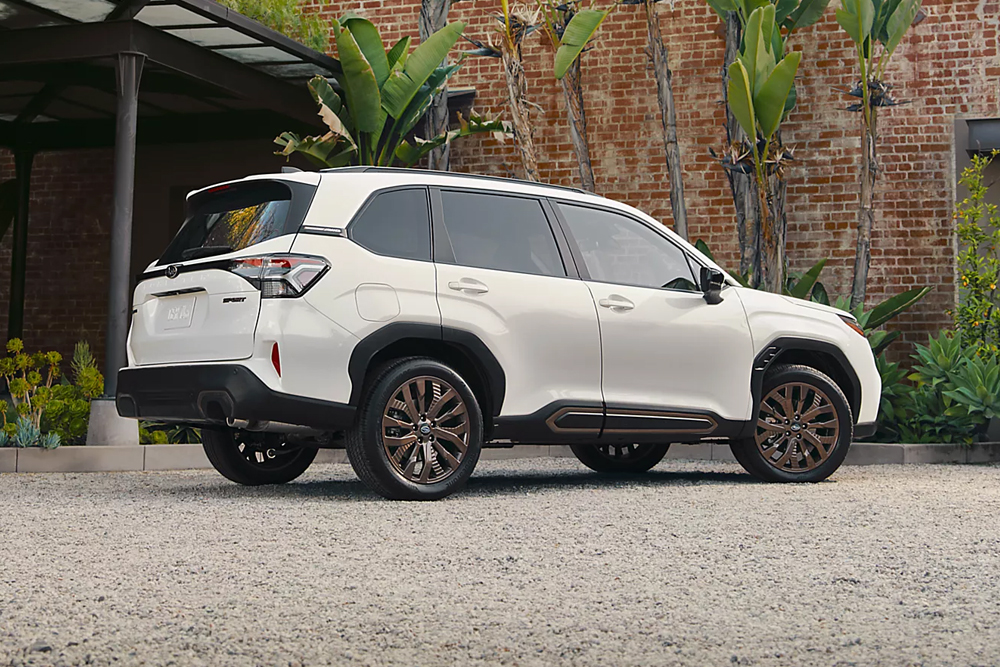 White 2025 Subaru SUV parked outside of brick industrial building with palm trees and succulent landscaping